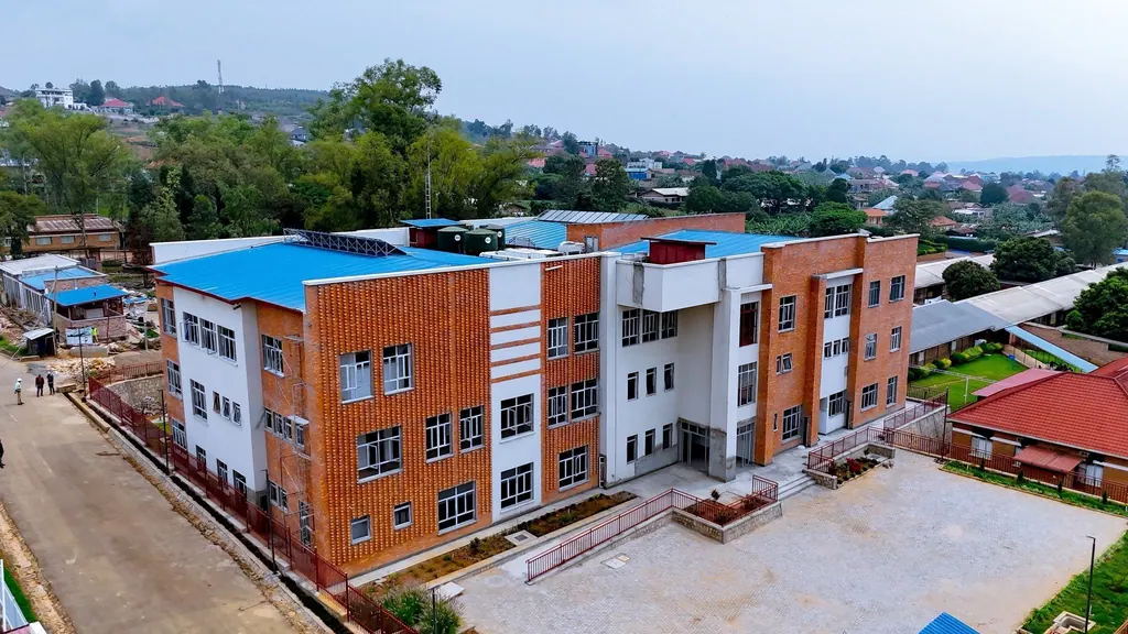 Aerial view of a brick hospital building with red roofs surrounded by trees.